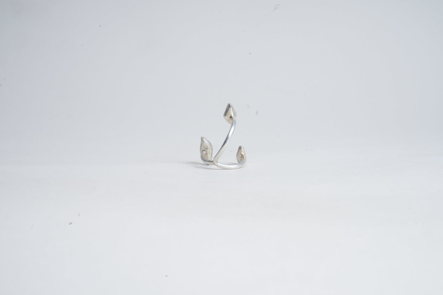 Silver earring on a light gray background