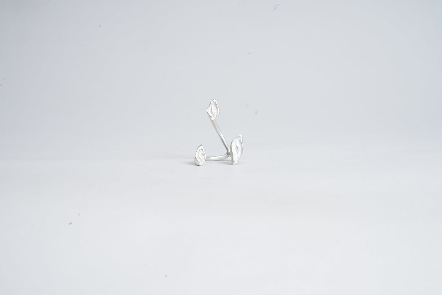 Silver earring on a light gray background