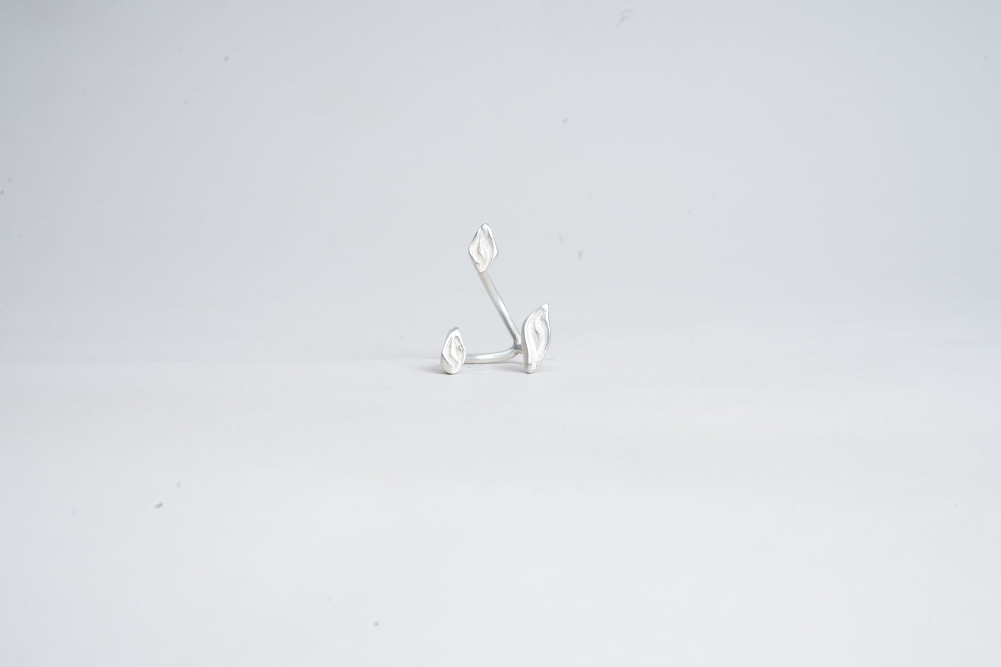 Silver earring on a light gray background