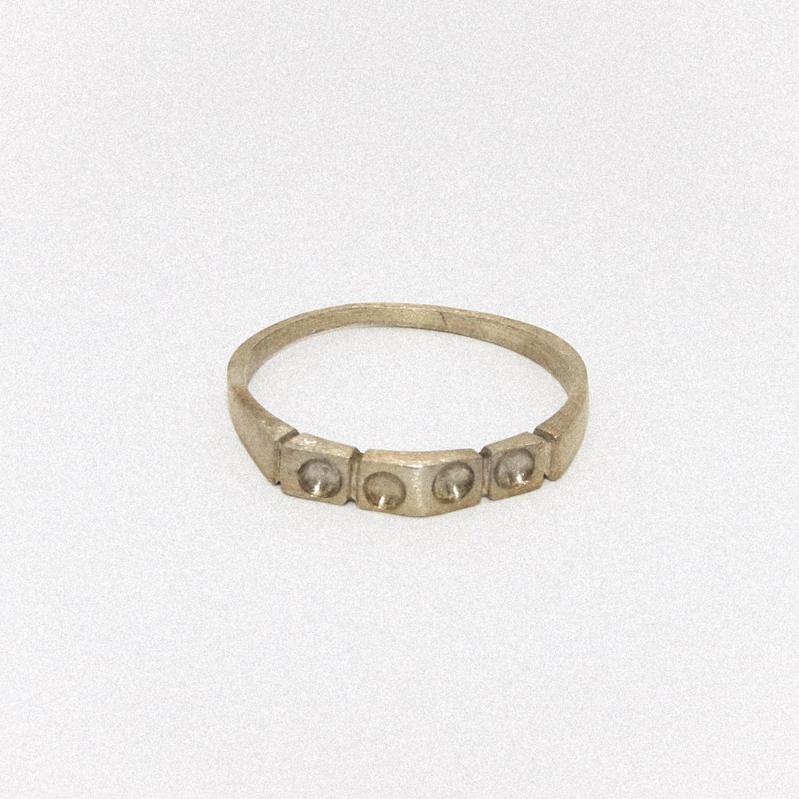 Silver ring with embedded stones on a light gray background