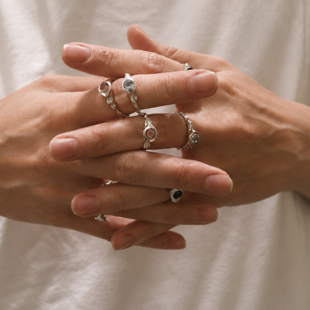 Close-up of hands wearing multiple rings with a neutral background