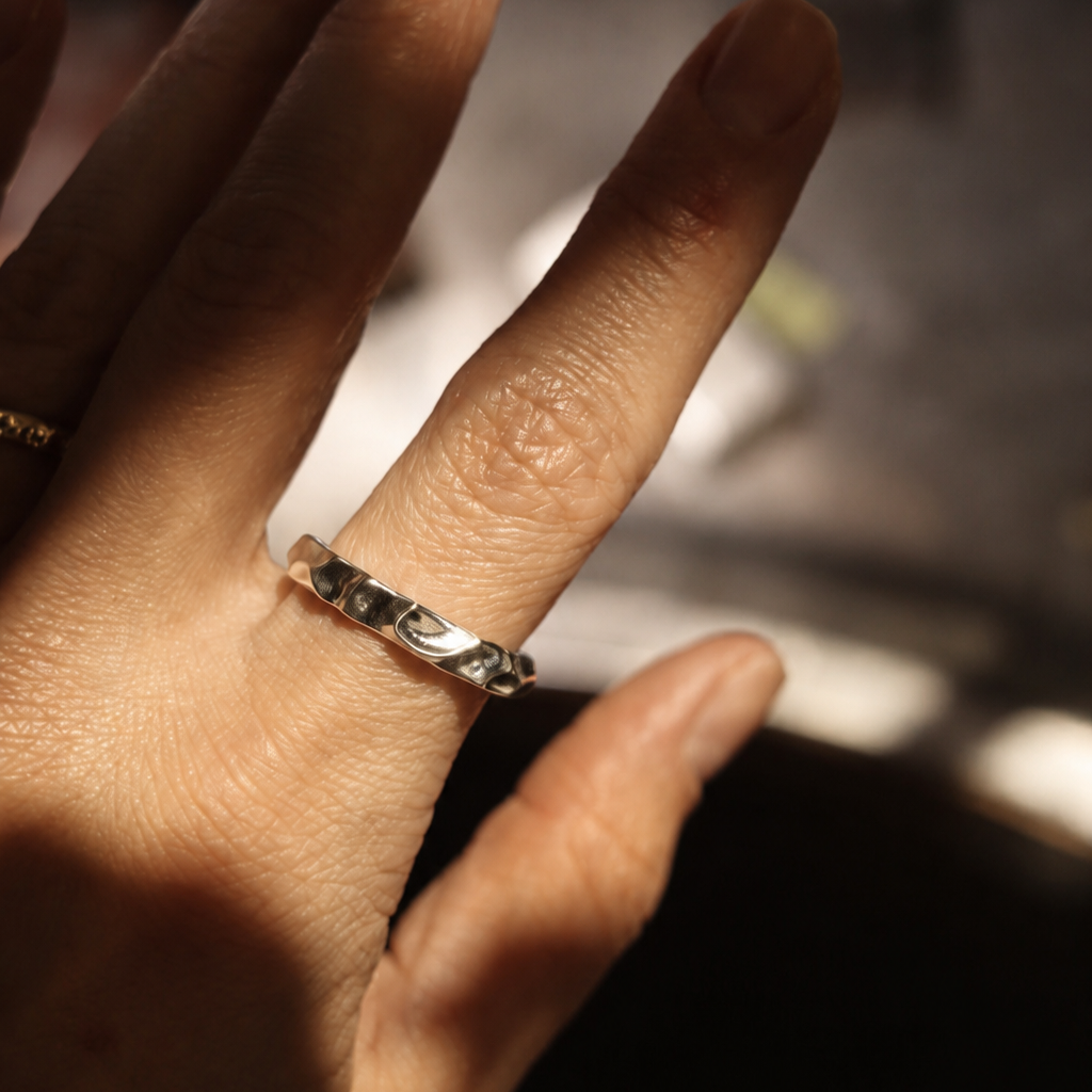 Close-up of a hand wearing a silver ring with a blurred background